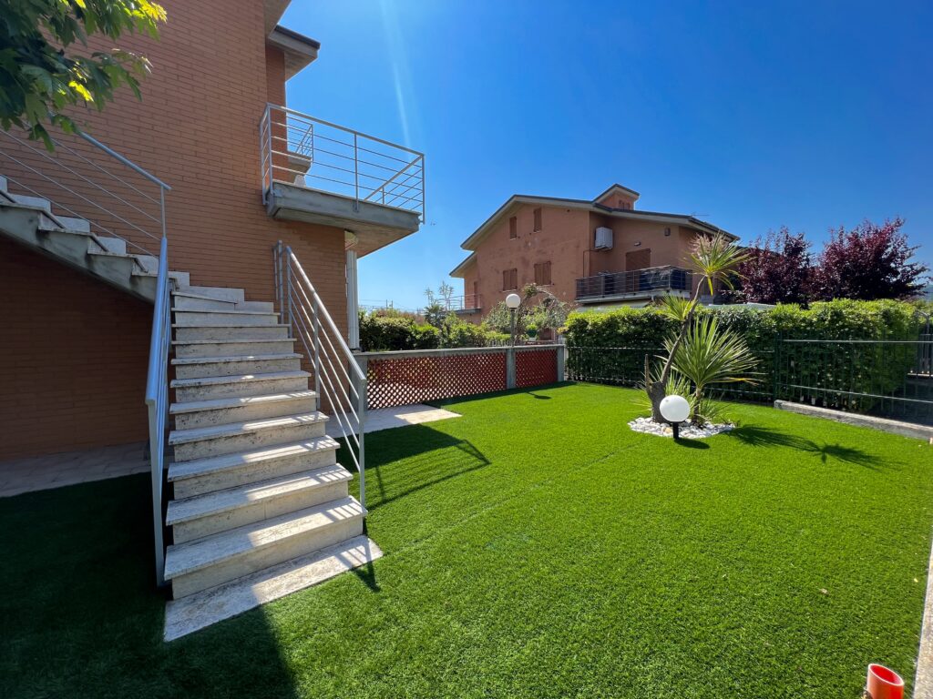 Giardino privato con erba artificiale e piante ornamentali
